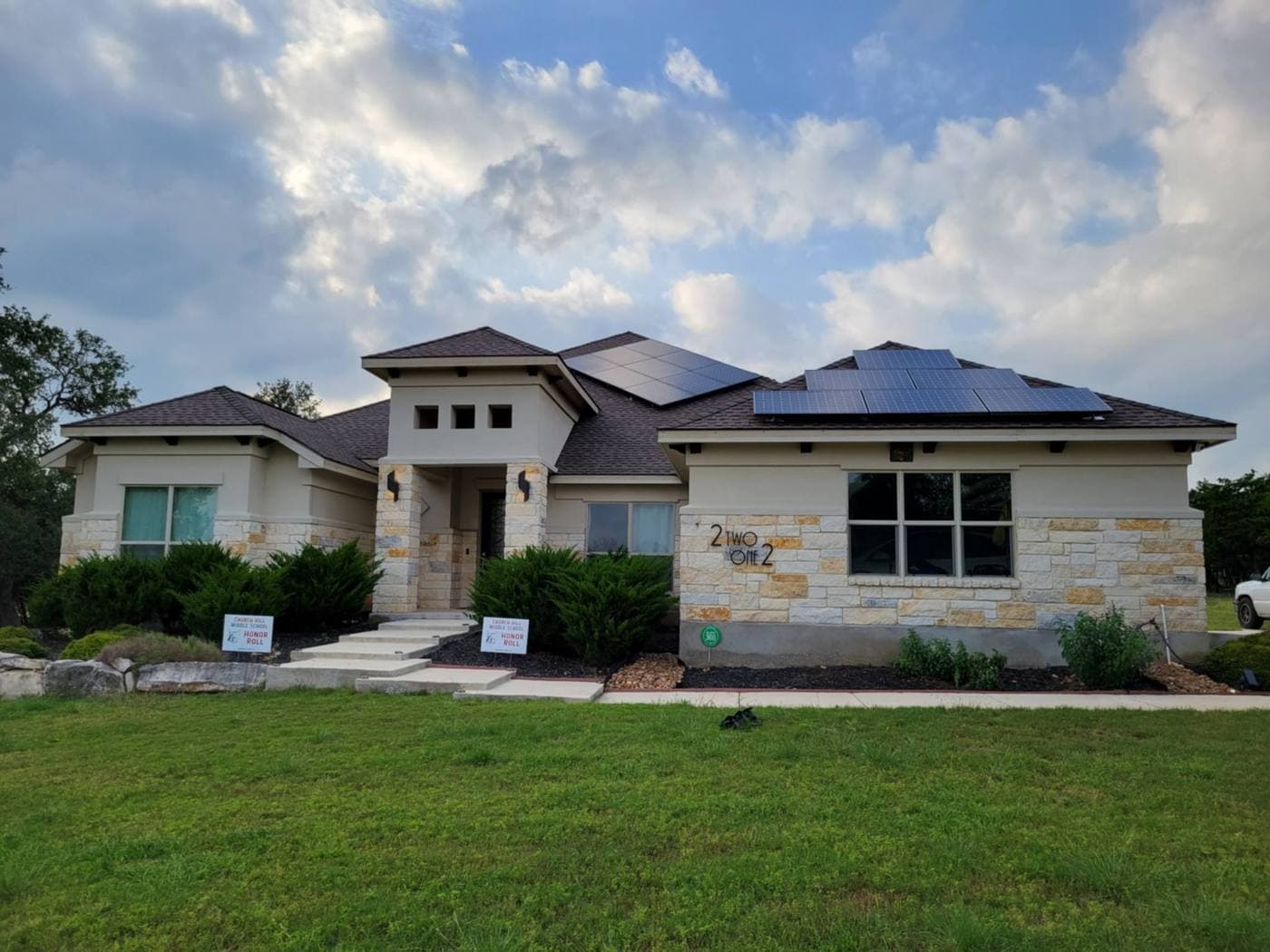 Hill Country stone home with rooftop solar panels at dusk
