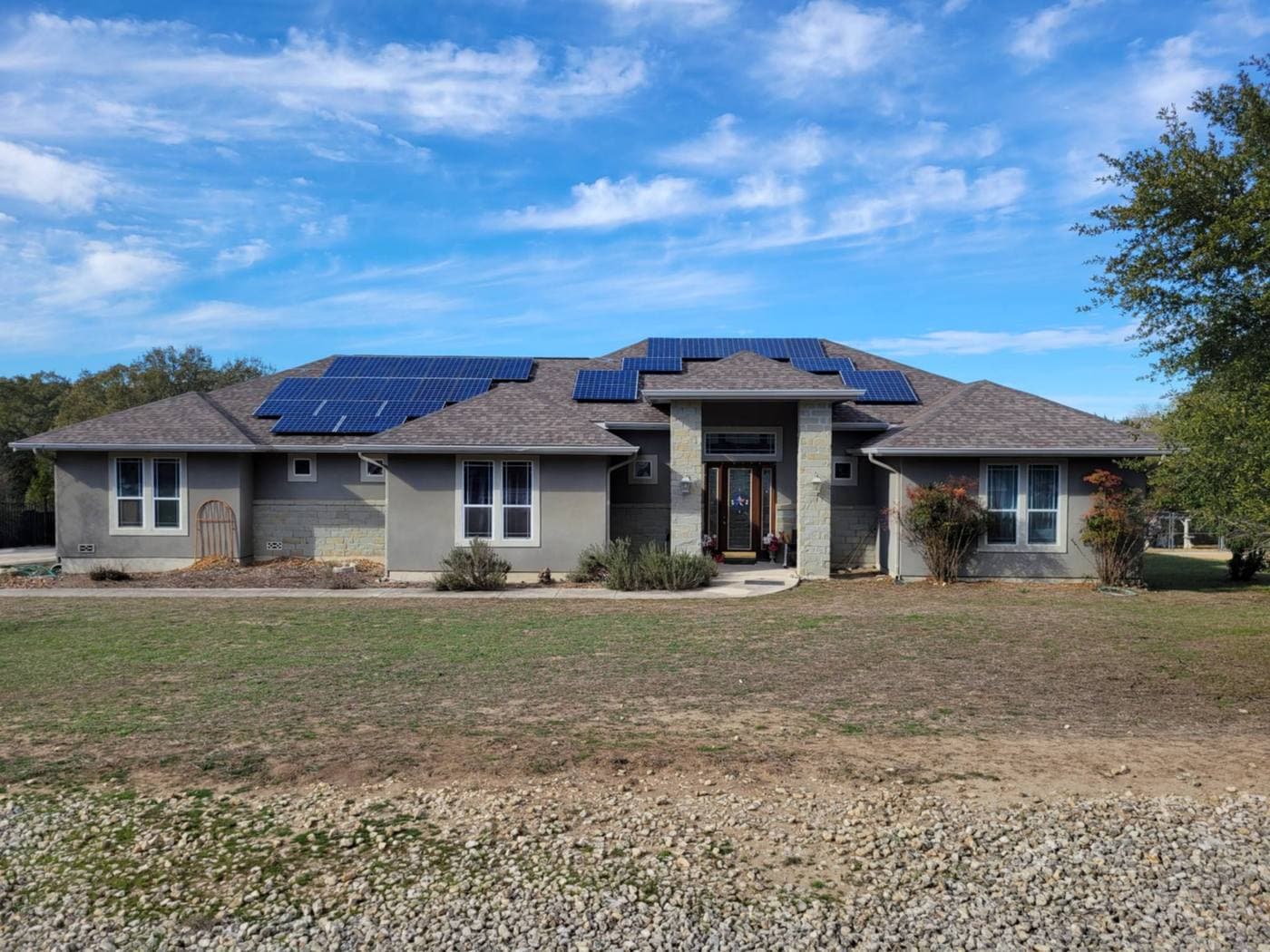 Single-story stucco home with rooftop solar panels under a clear sky