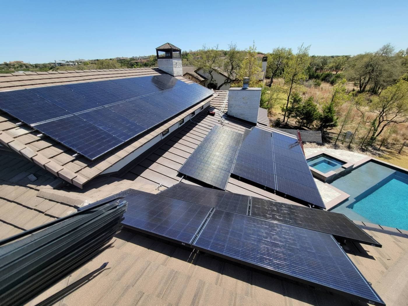 Aerial view of a tile roof solar array beside a pool and spa