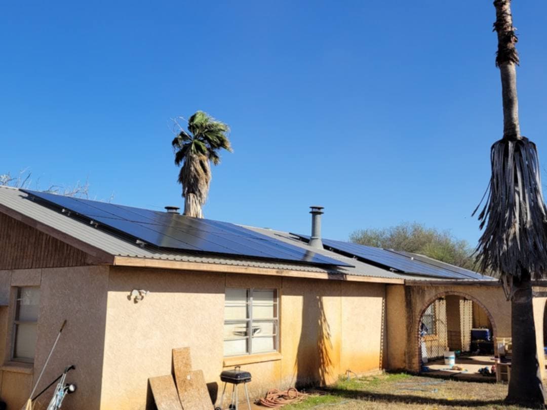 Single-story home with rooftop solar panels and palm trees